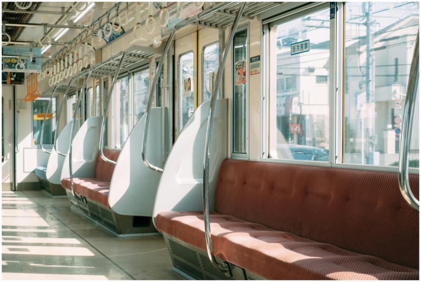 Sunlit empty train interior with red seats and mod