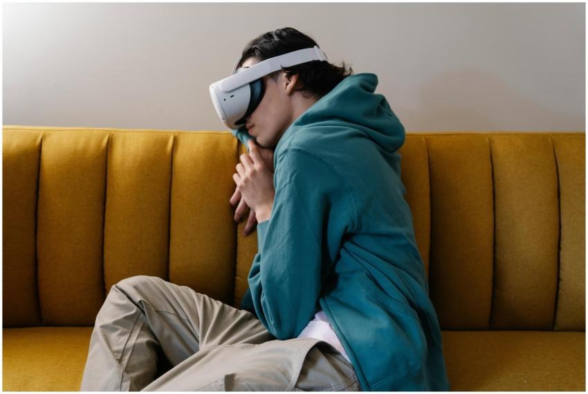 A young man in a hoodie rests with a VR headset on