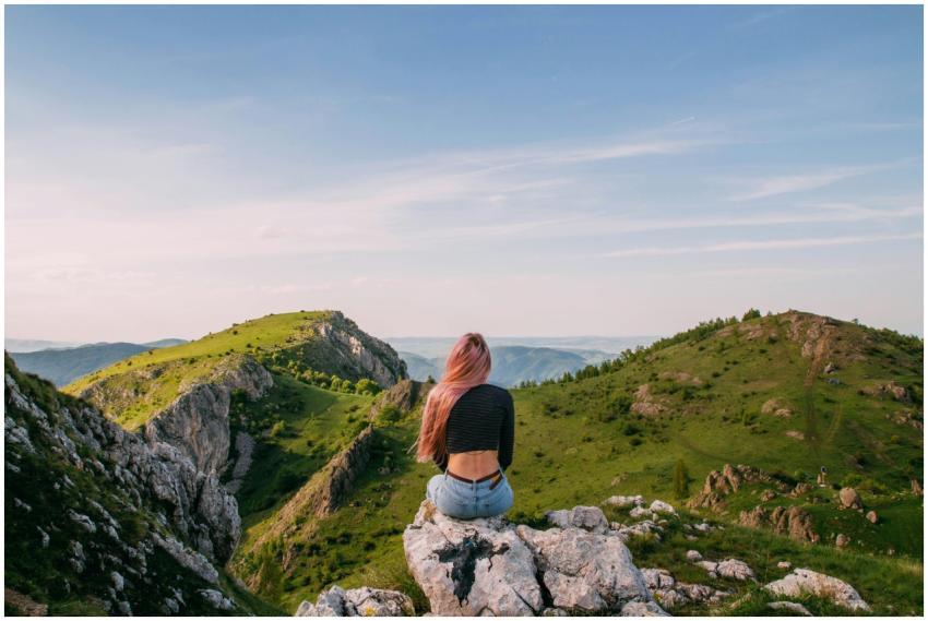 Woman sitting on rock with scenic mountain view in