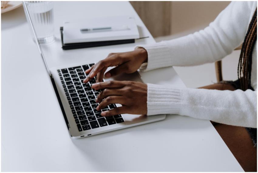 Close-up of woman's hands typing on a laptop in a