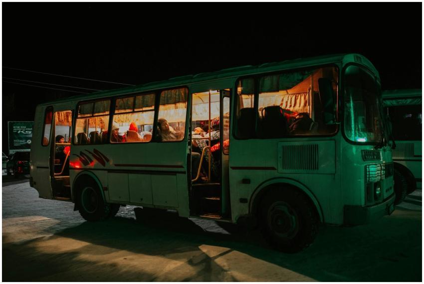 A bus parked at night with passengers visible insi