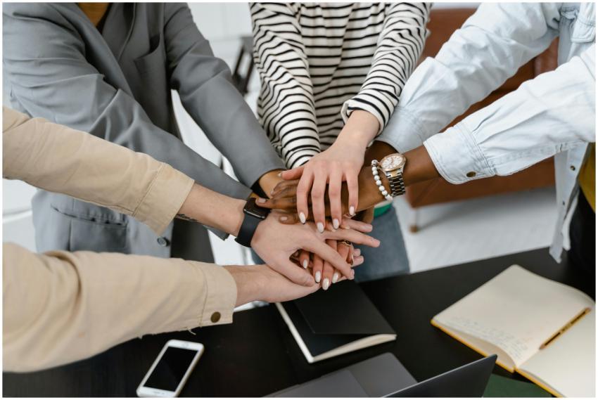 A group of diverse colleagues joins hands in teamw