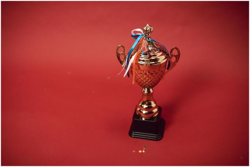 Golden trophy cup with red, blue, and white ribbon