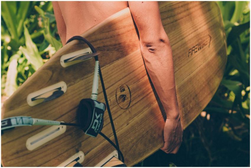 Close-up of a surfer holding a wooden surfboard am