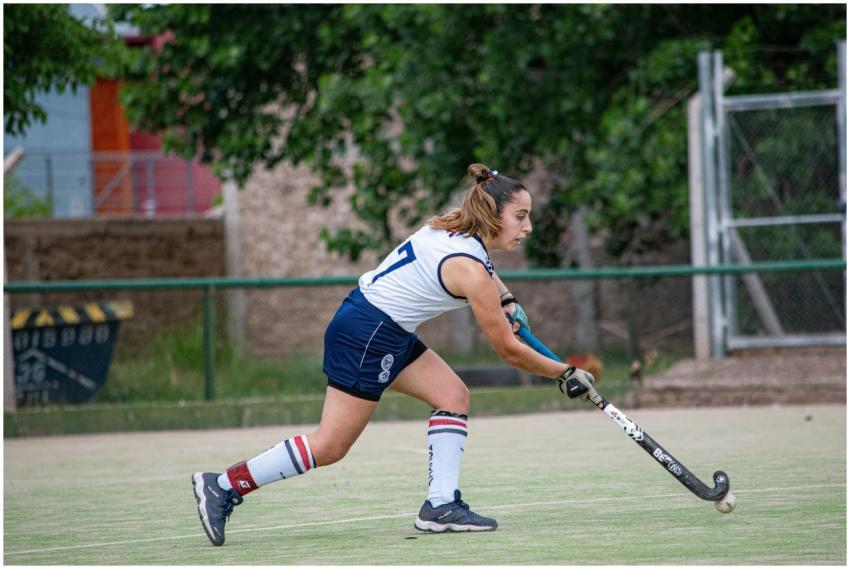 Female field hockey player striking the ball durin