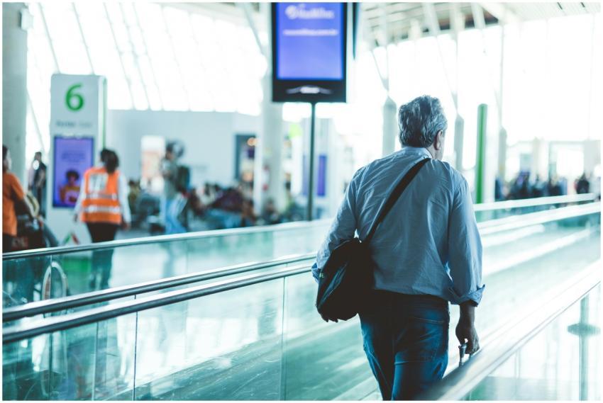 An adult male walking on an airport travelator, ca