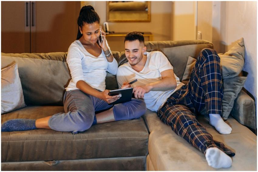 Interracial couple laughing and shopping online at