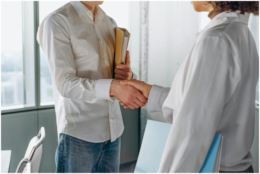 Two professionals shake hands indoors, symbolizing