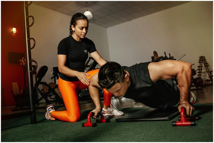 A fitness trainer assists a man in performing push