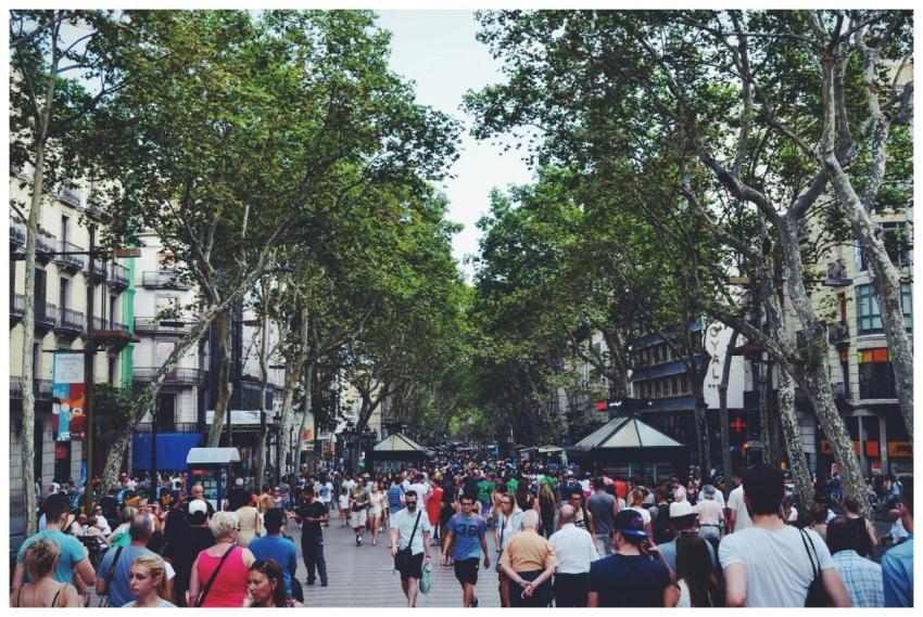A vibrant street filled with people and trees, sho