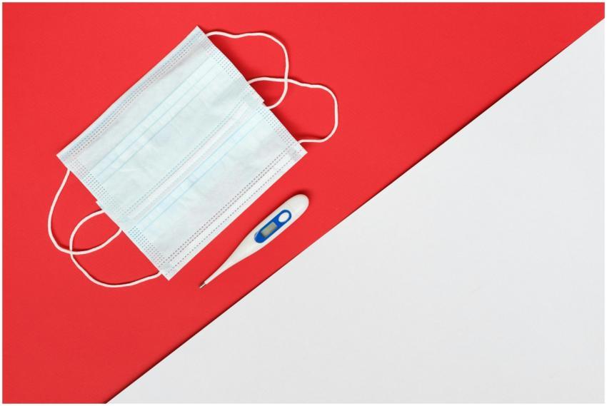 Flat lay of a face mask and digital thermometer on