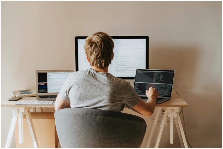 Teen programming with multiple laptops in a modern