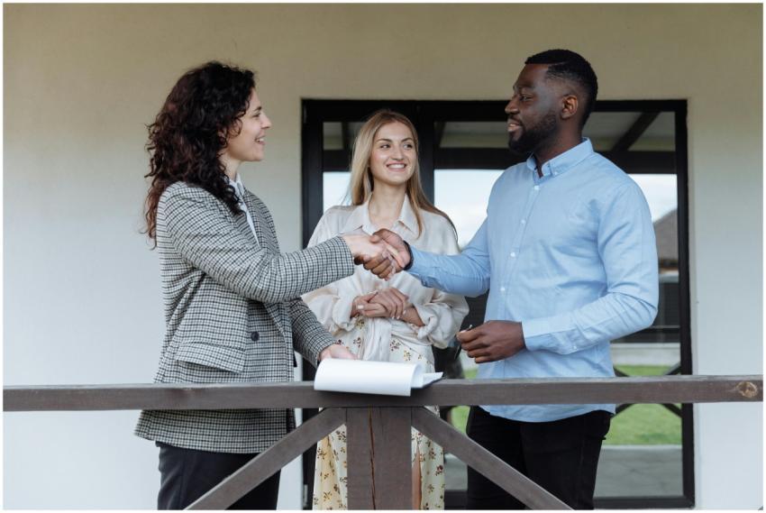 Three adults sealing a real estate deal with a han
