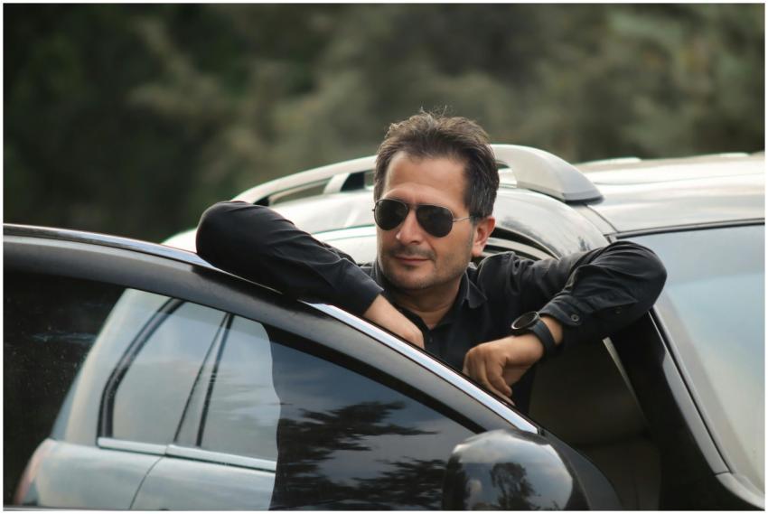 Man leaning out of a car window wearing sunglasses