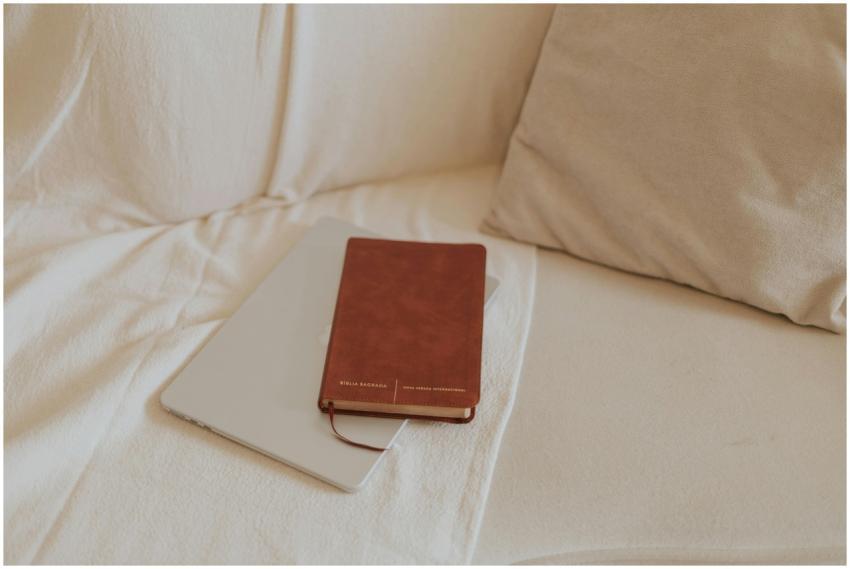 A Bible rests on a tablet on a cozy beige sofa, cr