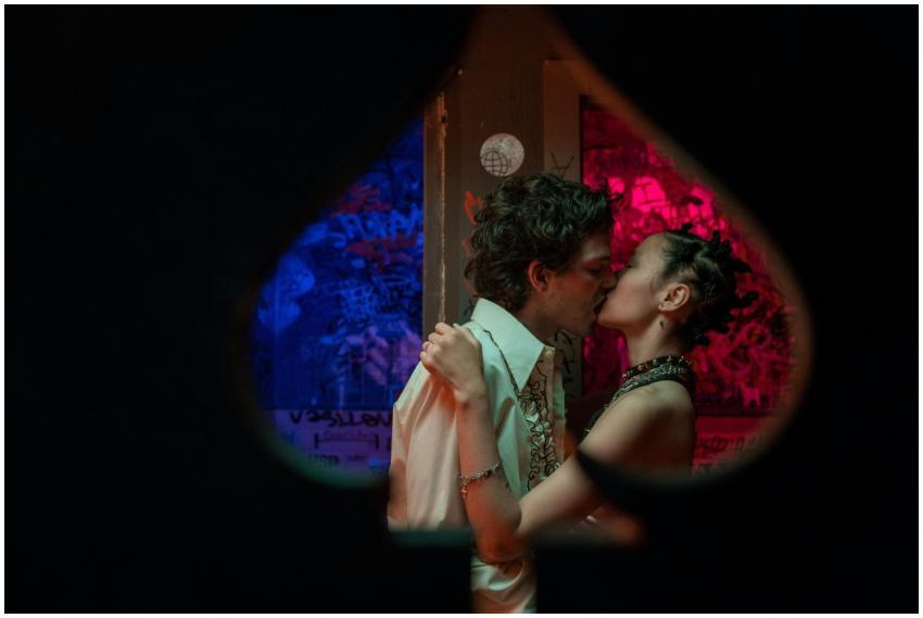 A couple shares a passionate kiss in a dimly lit c