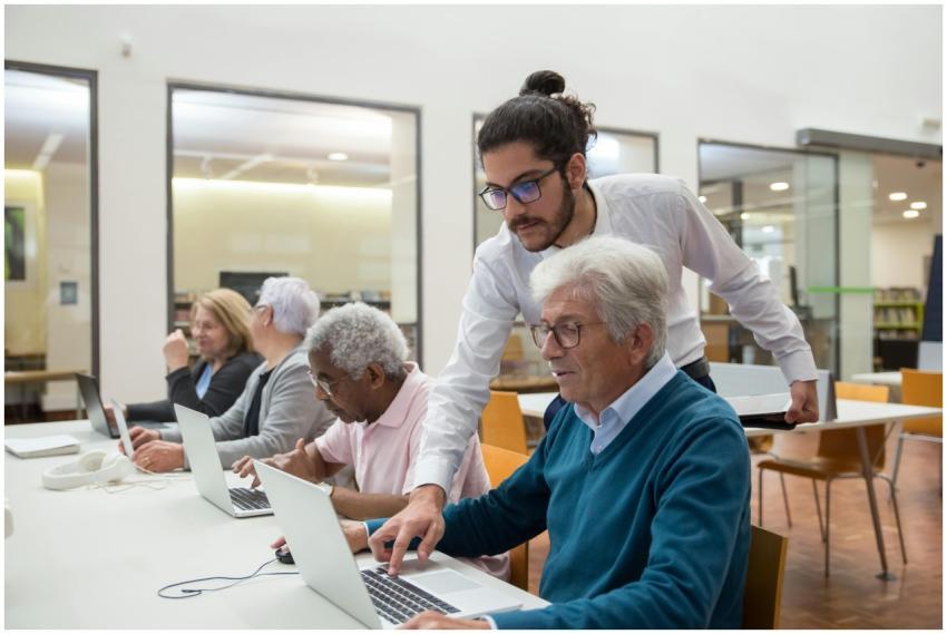 A teacher guiding senior adults in a library, usin