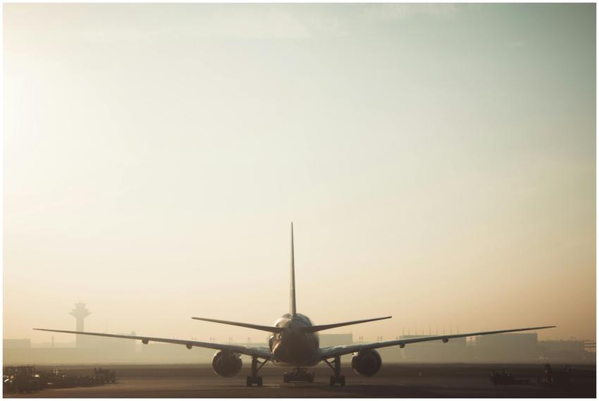 A misty morning scene of a plane on the runway wit