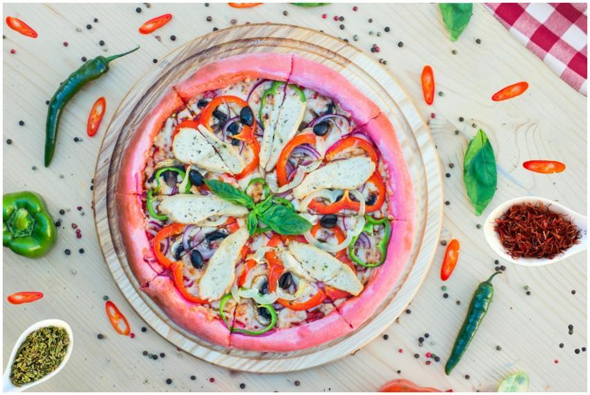 Colorful pink crust pizza with vegetables and herb
