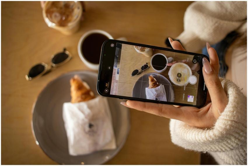 Woman photographing coffee and croissant with smar