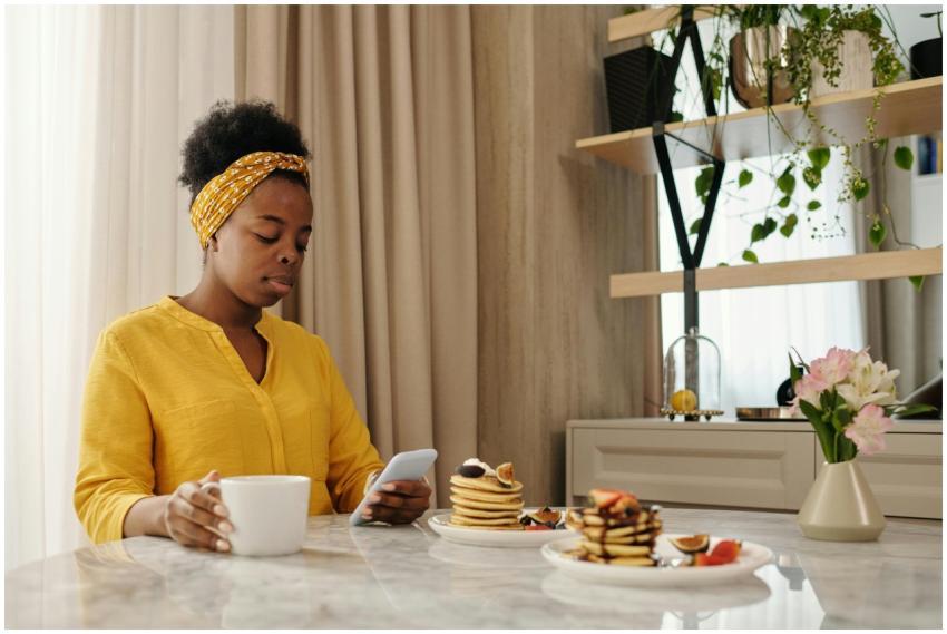 African American woman using smartphone while havi
