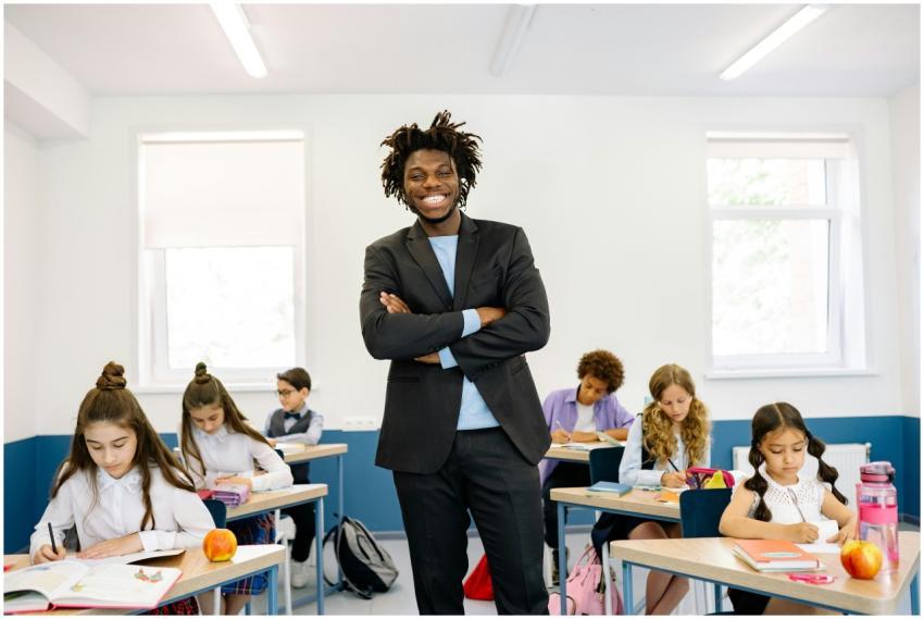 Smiling teacher standing in diverse classroom with