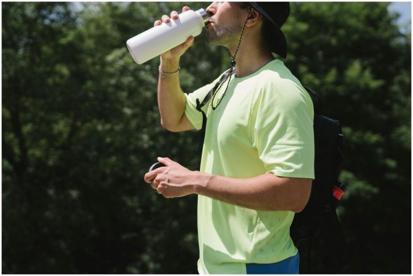 Adult man staying hydrated while hiking outdoors o