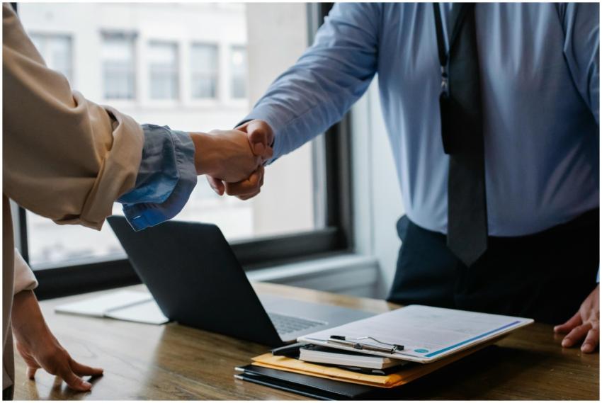 Crop unrecognizable coworkers in formal wear stand