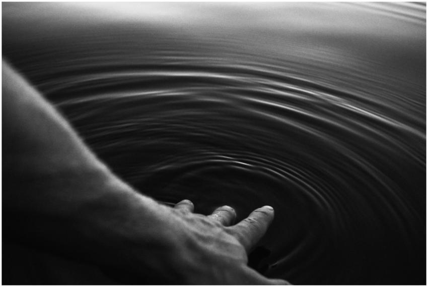 Black and white image of a hand creating ripples i