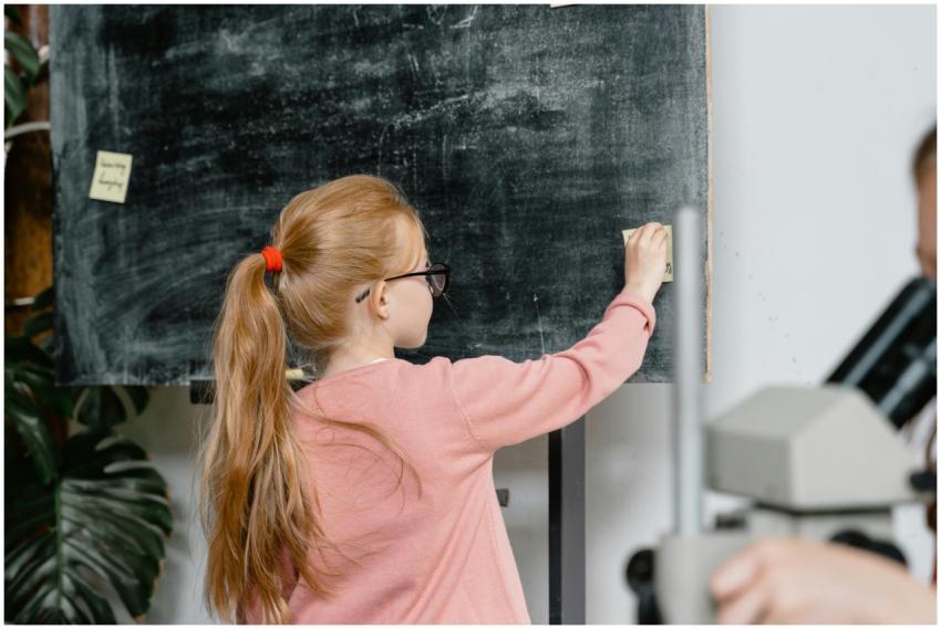 Child writing notes on blackboard in an educationa