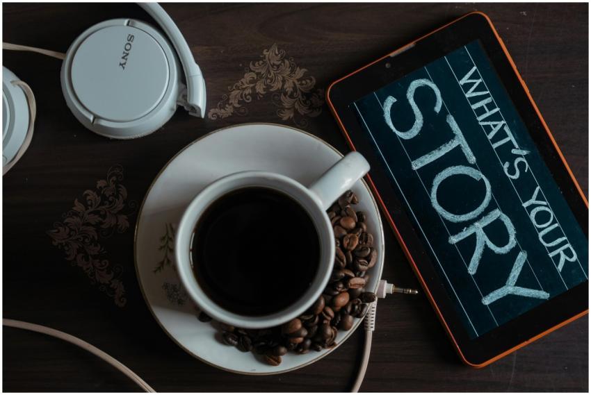 Flat lay of coffee cup, headphones, and tablet wit