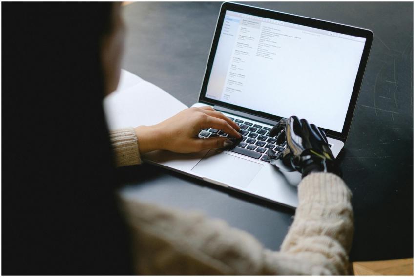 A person with a prosthetic hand using a laptop, sh