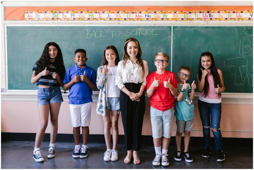 A diverse group of students and a teacher stand sm