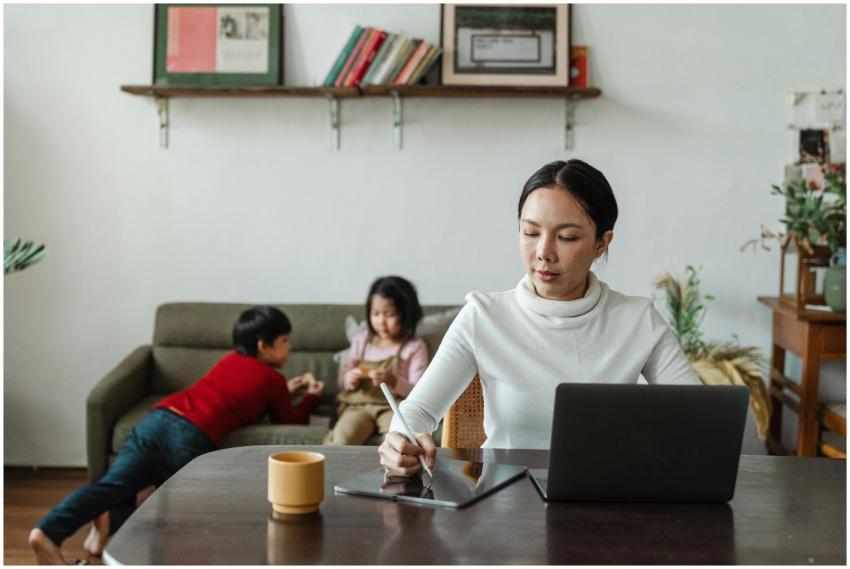Mother multitasking with laptop and stylus alongsi