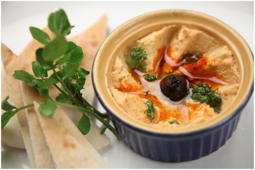 A close-up of creamy homemade hummus with pita sli
