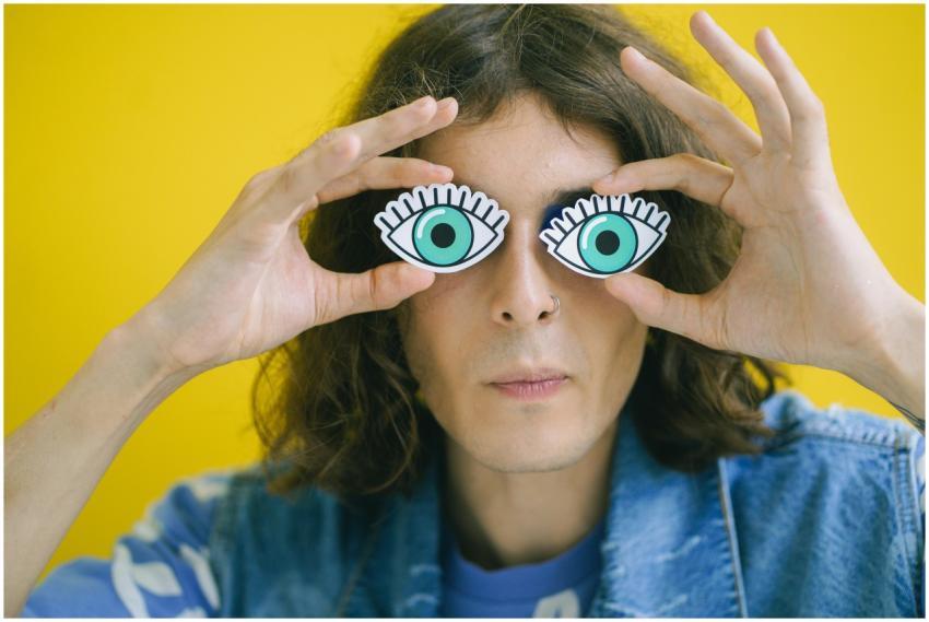 Man holding cartoon eye masks over face, playful a