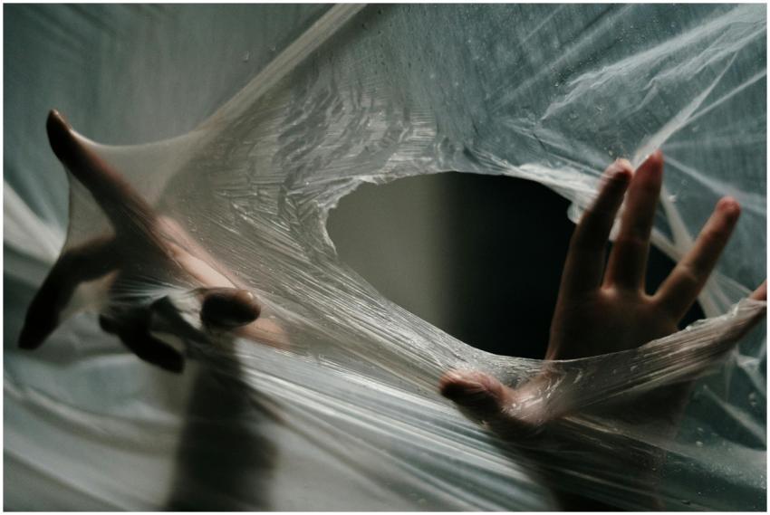 Hands emerging through a plastic sheet, symbolizin