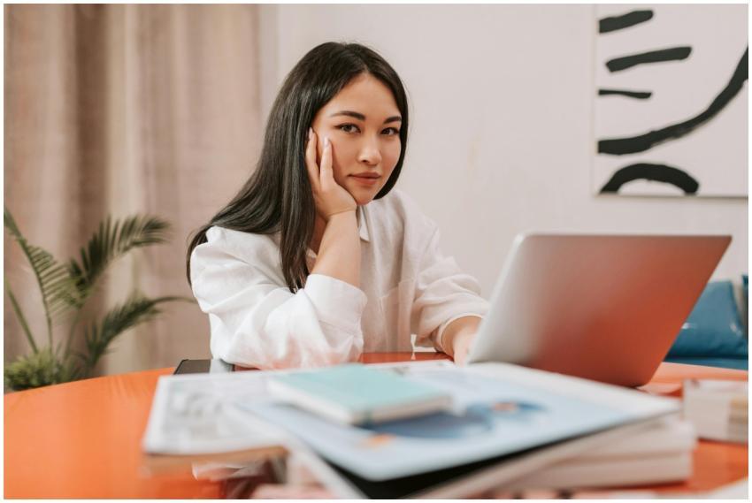 Young Asian woman sitting at desk with her hand on