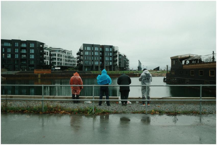 Four people in rain gear at a waterfront, surround
