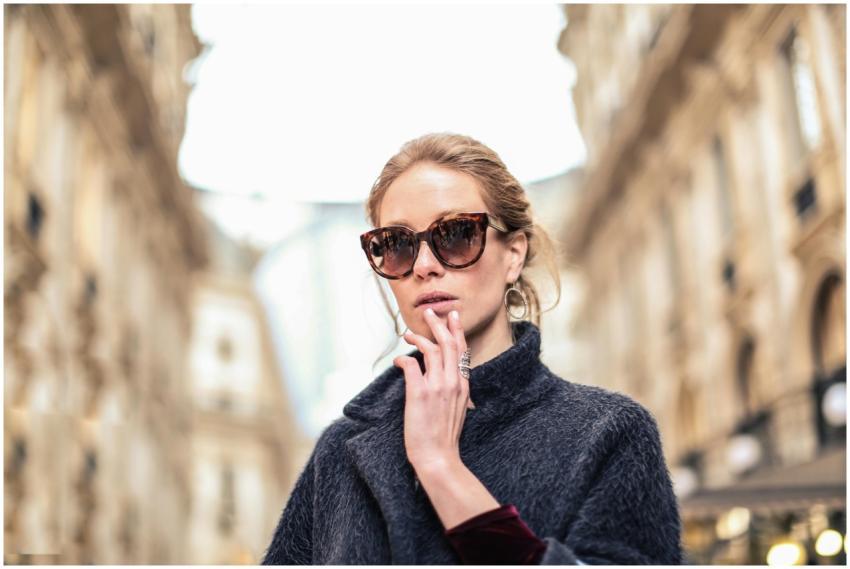 Elegant woman in sunglasses posing outdoors in a f