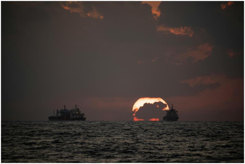 Two ships silhouetted against a stunning sunset on