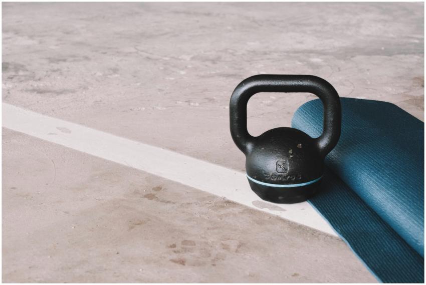 Kettlebell and blue yoga mat on a concrete floor i