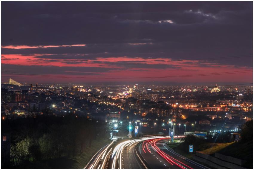 A vibrant cityscape at night featuring light trail