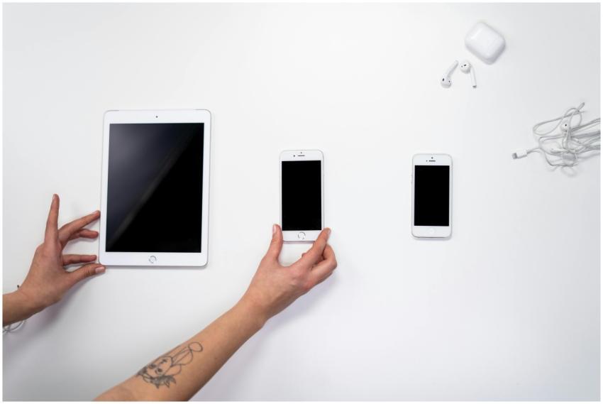 Top view of hands arranging an iPad, iPhones, and
