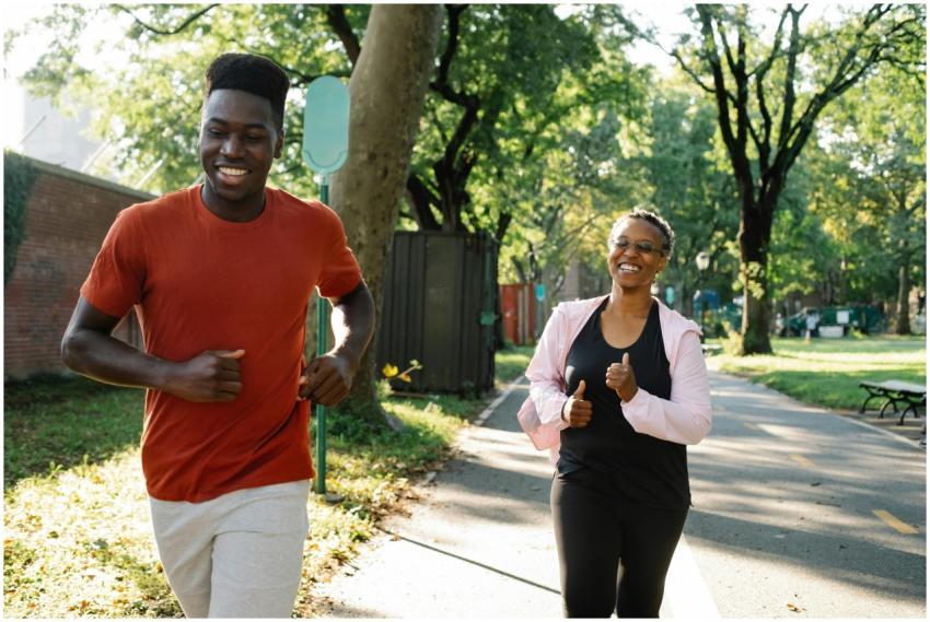 A smiling couple jogging together in a sunny park