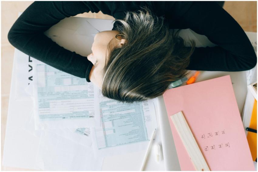 Exhausted woman resting her head on a desk clutter