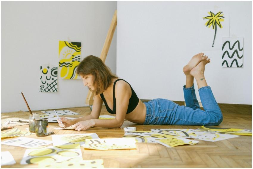 A focused woman lying on the floor creating artist