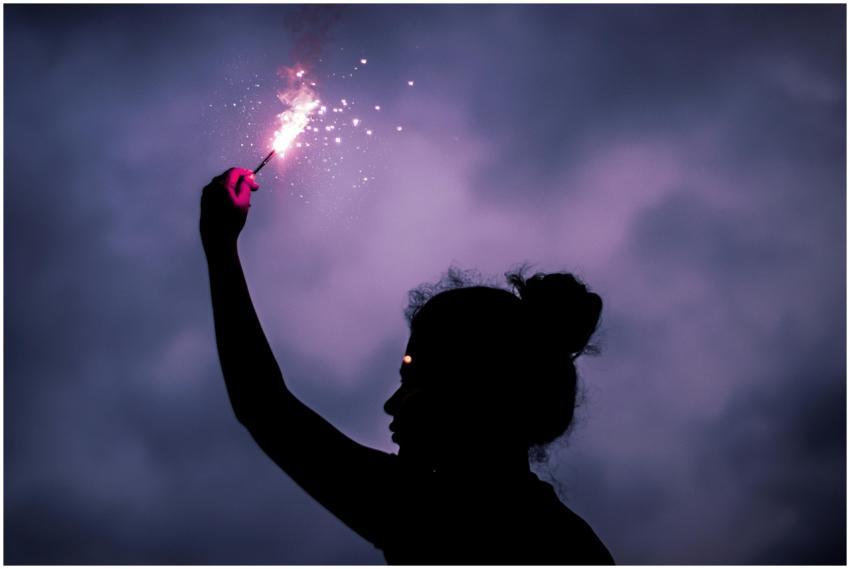 Silhouette of a woman with a glowing sparkler agai