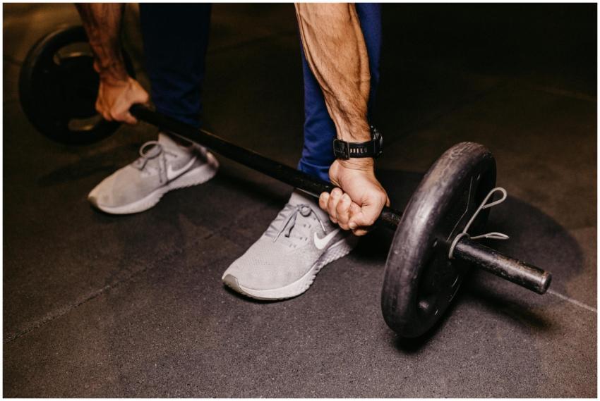 Close-up of a person lifting a heavy barbell indoo