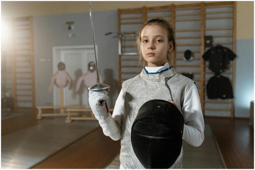 A young female fencer in full gear holding a foil